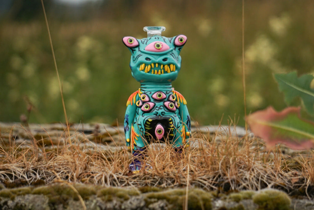 Handgefertigtes Monster Dab Rig aus Glas in Türkis mit mehreren Augen und gelben Zähnen in der Natur