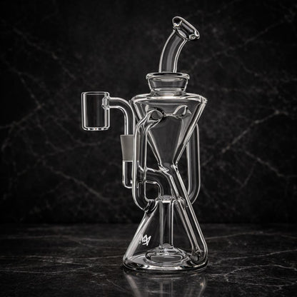 Clear glass recycler dab rig photographed at an angle with dark studio lighting