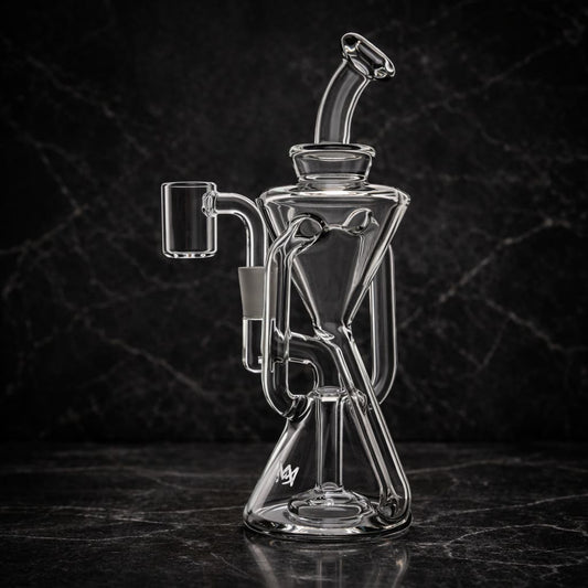 Clear glass recycler dab rig photographed at an angle with dark studio lighting