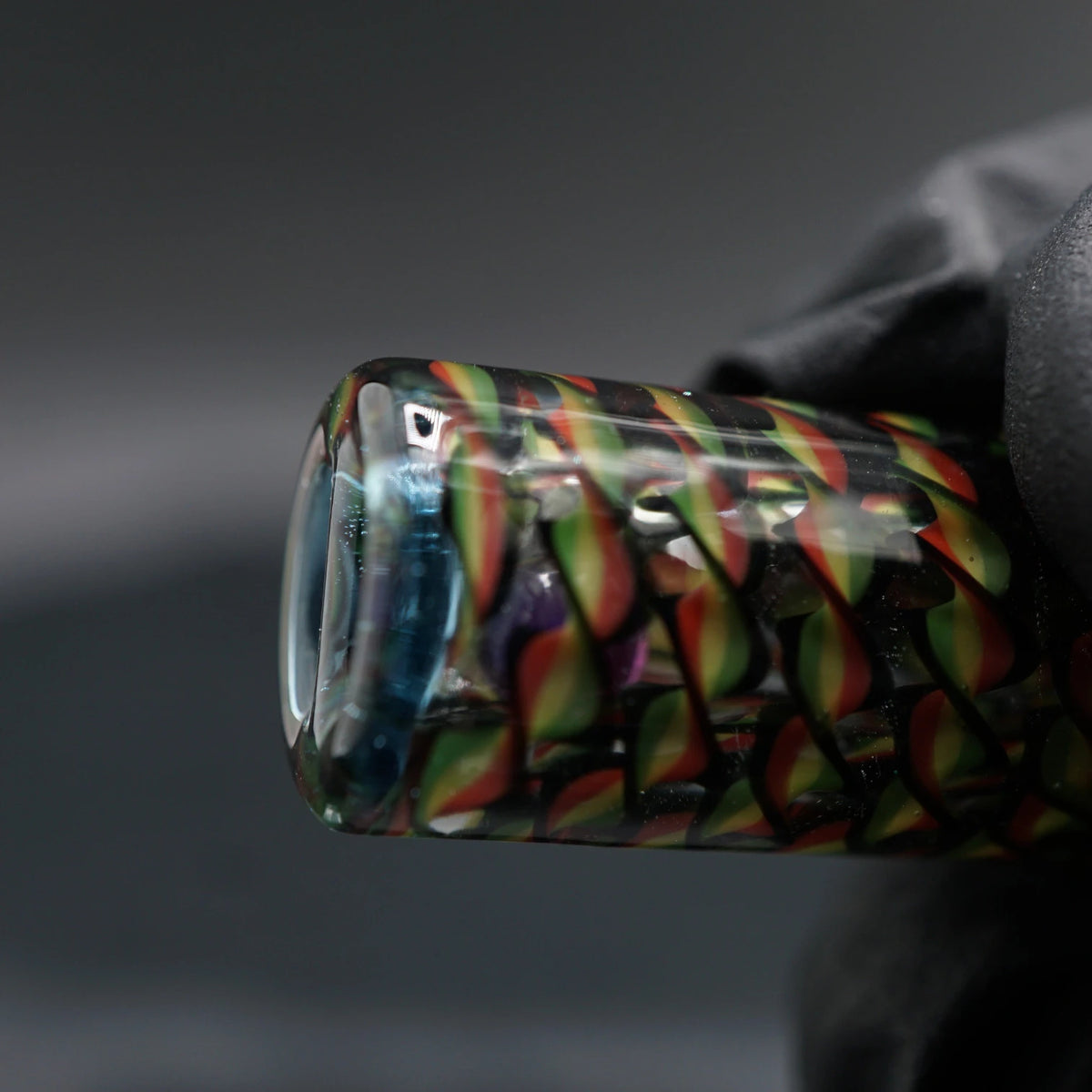 Nahaufnahme der rot-gelb-grünen Glaswindungen mit schwarzen Konturen und transparenten Zwischenräumen am Spray Can Roots Twist Glastip