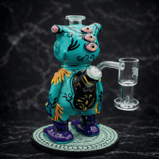 Seitenansicht eines handgefertigten Monster Dab Rigs aus Glas in Türkis mit Glasbanger und detailreicher Bemalung