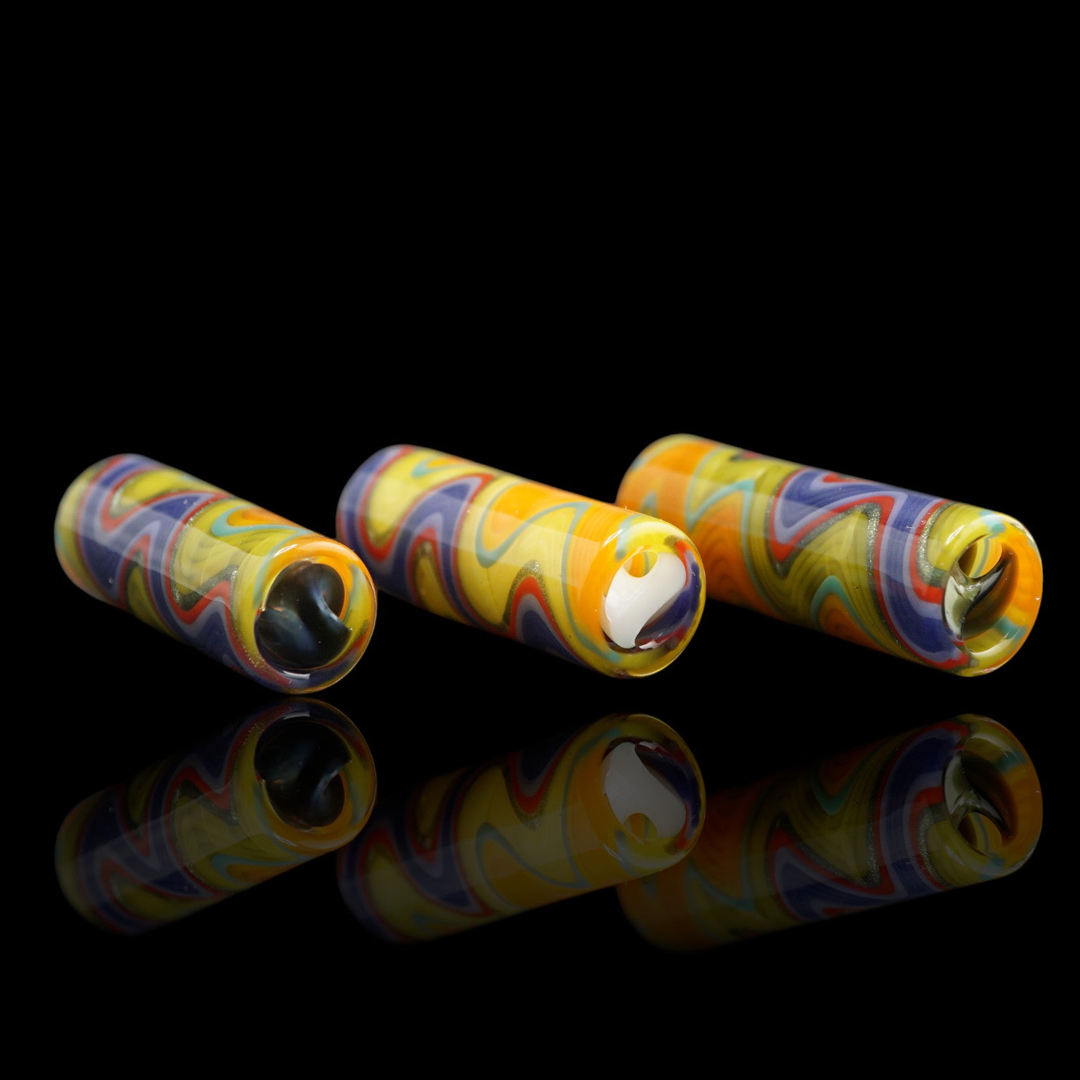 Three Tyeglassarts Sunset Pulse glass tips displayed together with yellow orange purple and turquoise wave patterns